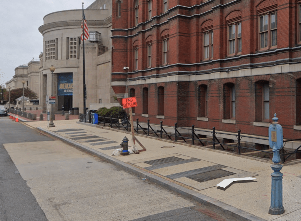 A view from ground, looking at two buildings, bus sign, and fire hydrant.